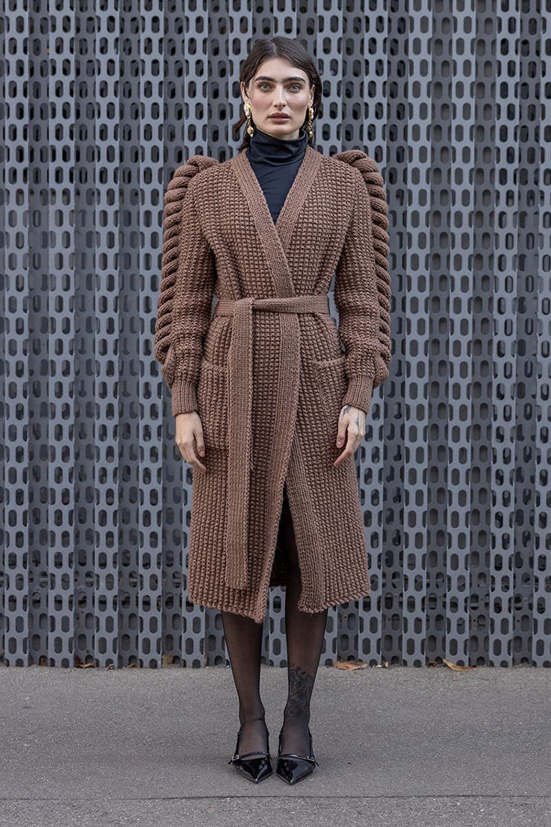 Dark brown hand-knitted coat by Liya, featuring cozy textured knit fabric and a stylish, warm design for winter wear.