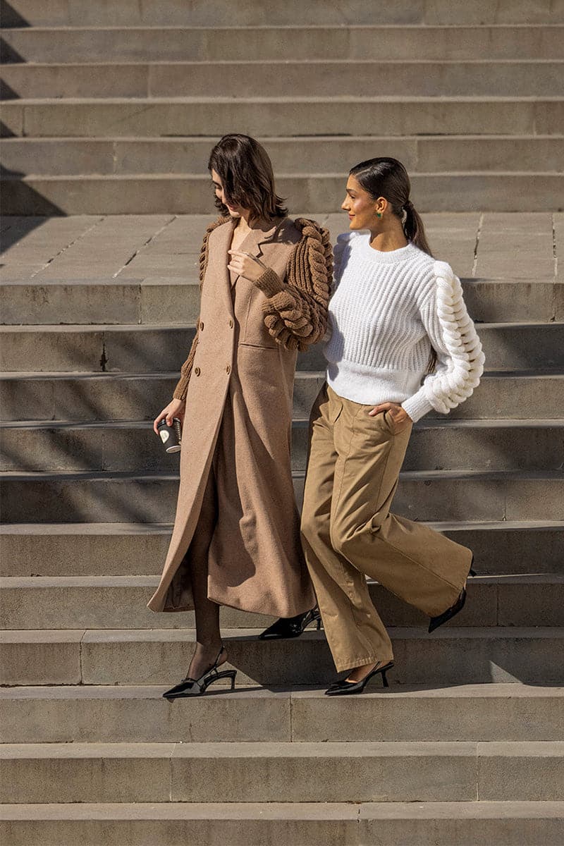 Liya camel double-breasted knitted sleeves coat displayed on a hanger, showcasing its warm, cozy design and camel brown color.