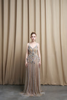 Beige spaghetti strap embroidered gown with beaded tulle skirt by HACCHIC COUTURE, elegant evening wear for formal occasions.
