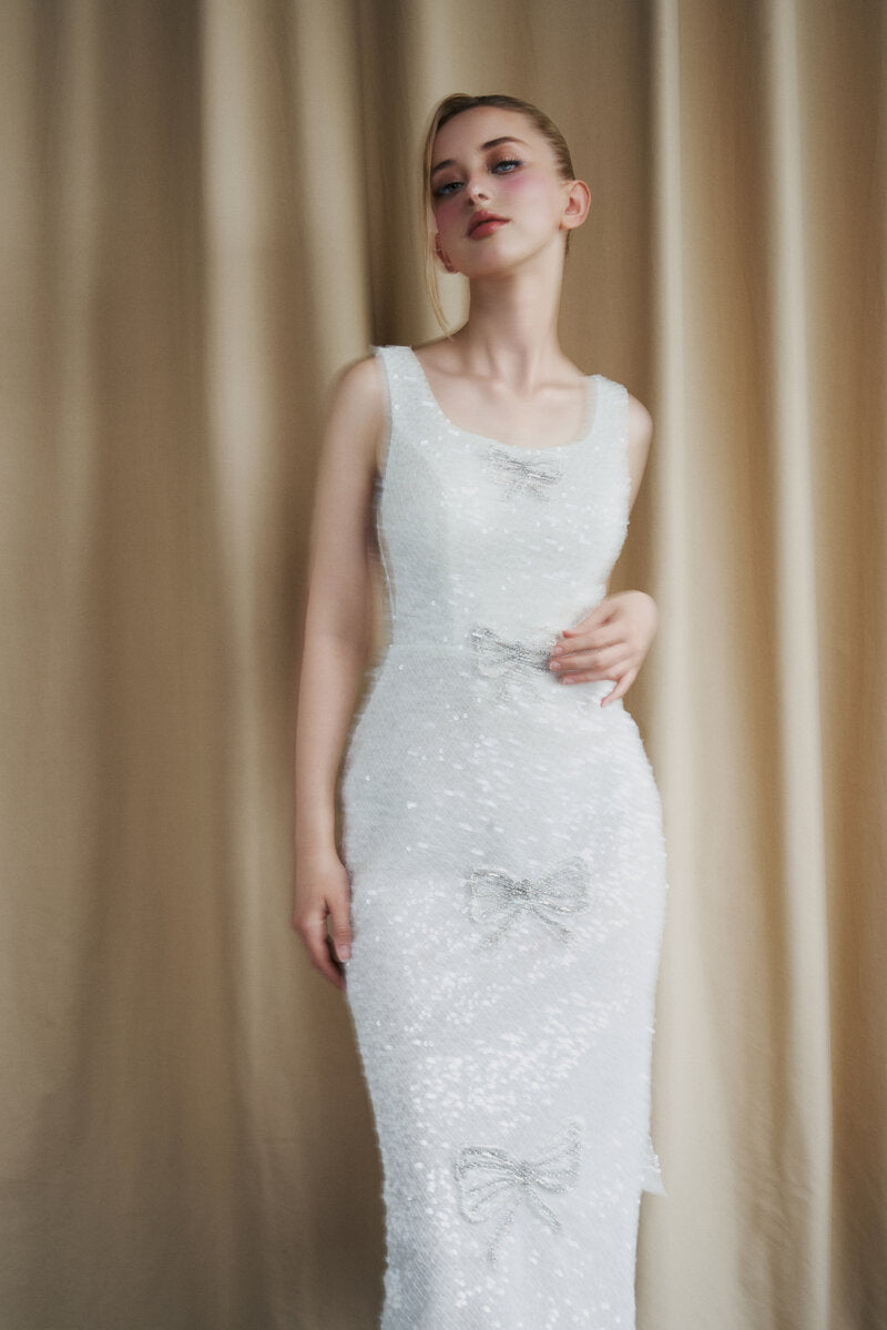 Ivory sequin gown with scoop neck and bow details from HACCHIC COUTURE, featuring elegant design and shimmering embellishments.