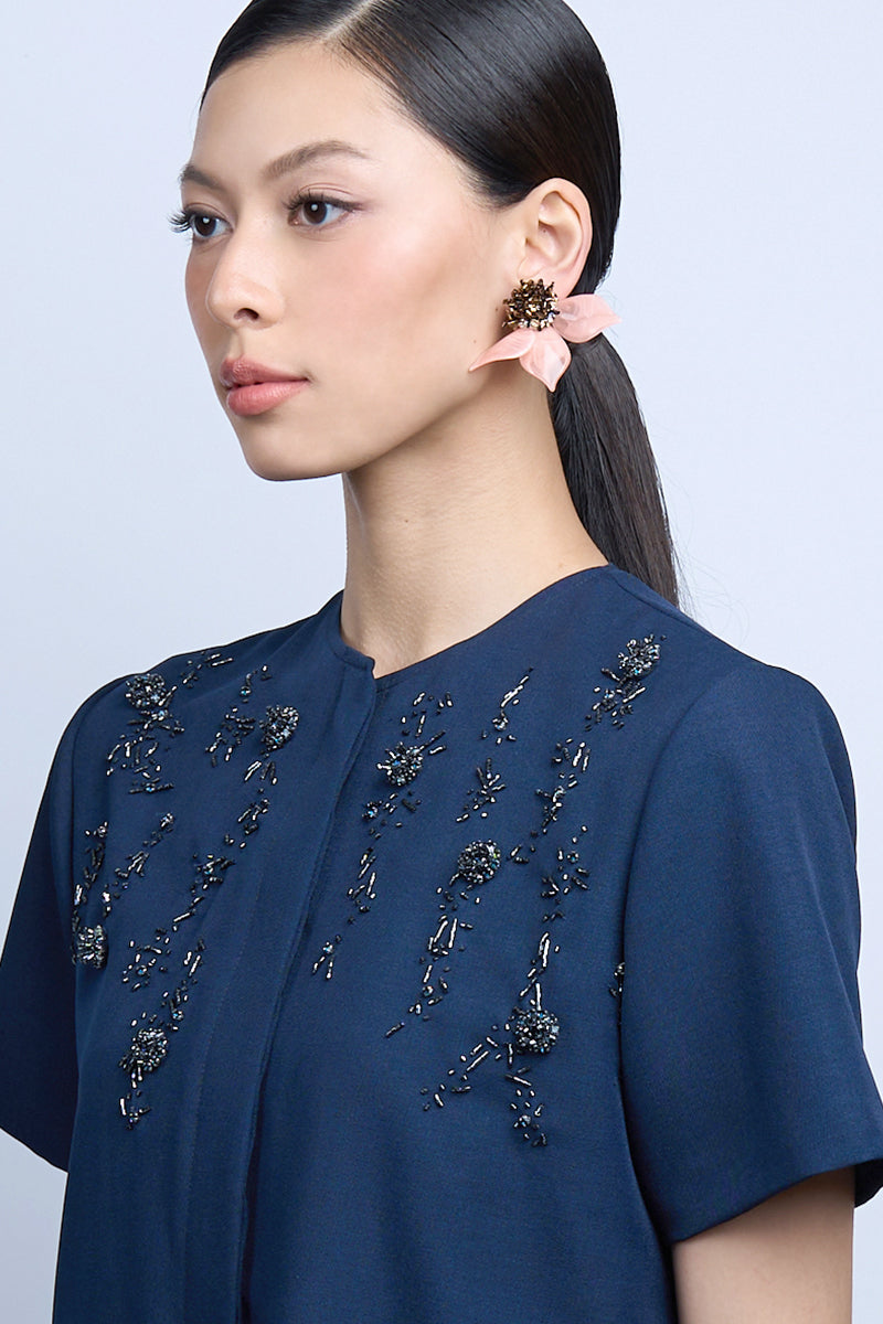 A pair of peach-colored dew drop earrings by Aidan & Ice, featuring delicate teardrop-shaped design on a white background.