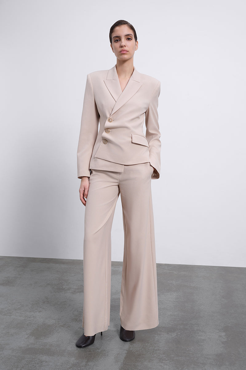 SÉLONE Oris asymmetrical tailored blazer in warm beige, featuring a modern twist and structured fit, on a neutral background.