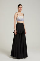 Black peplum maxi skirt from Nara Niro, featuring a fitted waist and flowing length, perfect for elegant casual wear.