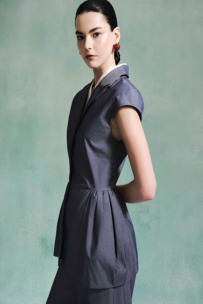 Lecia peplum top in black with fitted waist and flared hem, shown on a model against a neutral background.