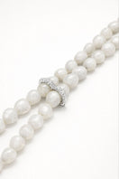 White cascade necklace by Jude Benhalim featuring layered, delicate chain design, displayed on a neutral background.