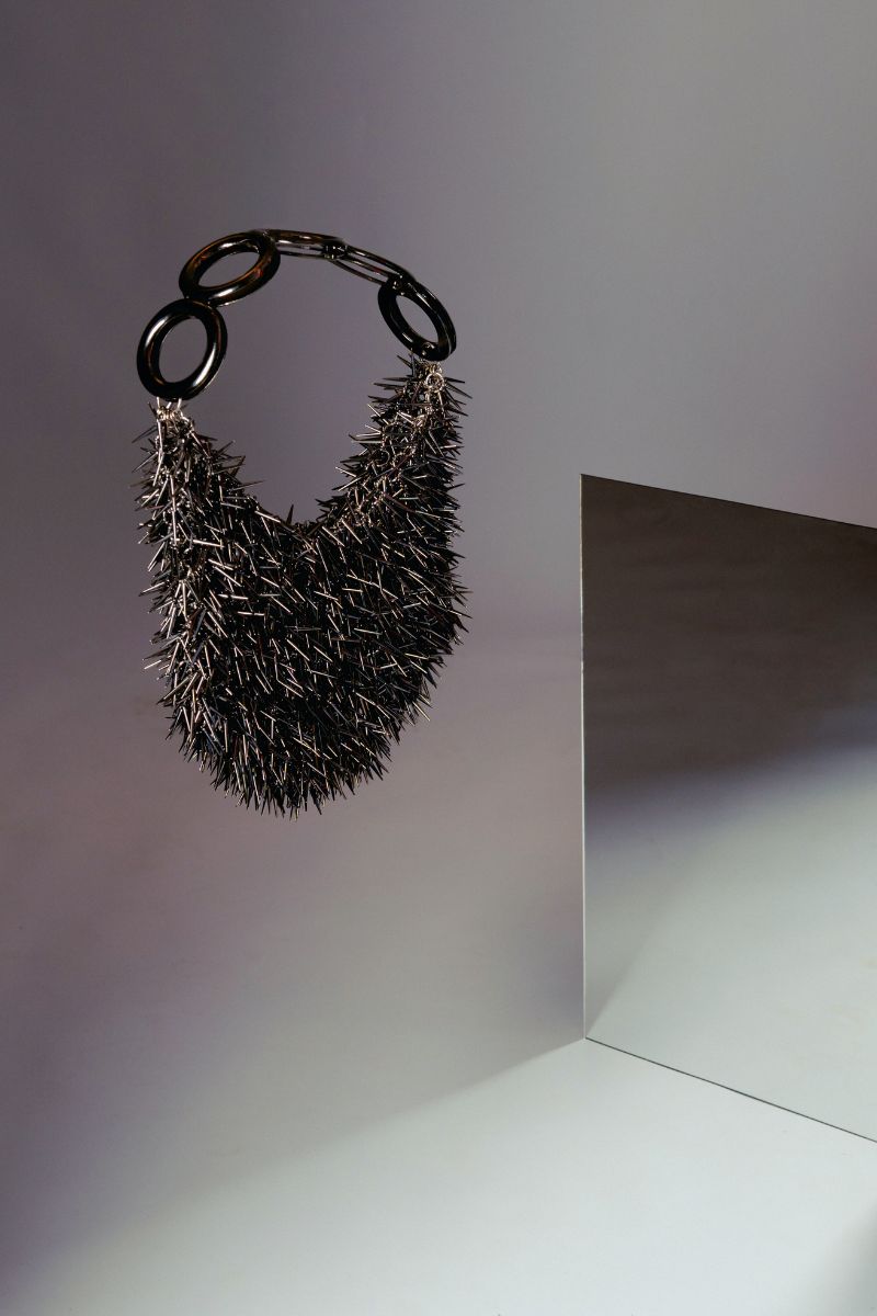 Gray punk-inspired metallic top handle bag by Millanne Tale with a bold, edgy design and silver finish.