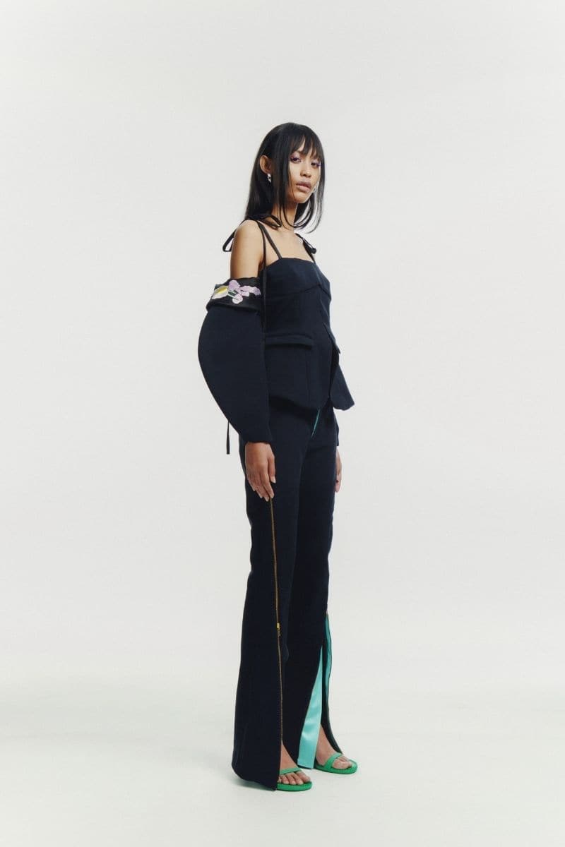 Black embroidered tailored top by Sean Sheila, featuring intricate embroidery and a fitted design, displayed on a black background.