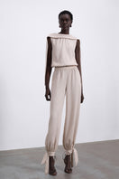 SÉLONE Selis balloon trousers in stone color with a relaxed fit and elastic waist, showcased on a hanger.