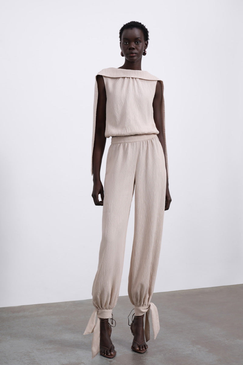 SÉLONE Selis balloon trousers in stone color with a relaxed fit and elastic waist, showcased on a hanger.