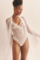 Sheer white mesh bodysuit by Luciela, featuring long sleeves and a fitted design, shown on a model.