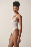 Sheer white mesh bodysuit from Luciela, featuring long sleeves and a fitted design, styled against a neutral background.