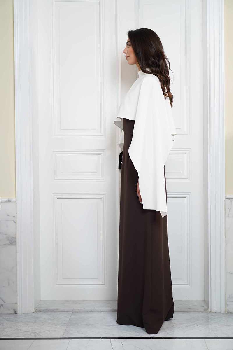 Joanna Andraos ivory evening gown with a flowing cape, detailed side view showcasing elegant fabric and sophisticated design.