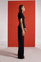 Joanna Andraos black crepe two-piece co-ord set with draped cape, shown from side angle on model.