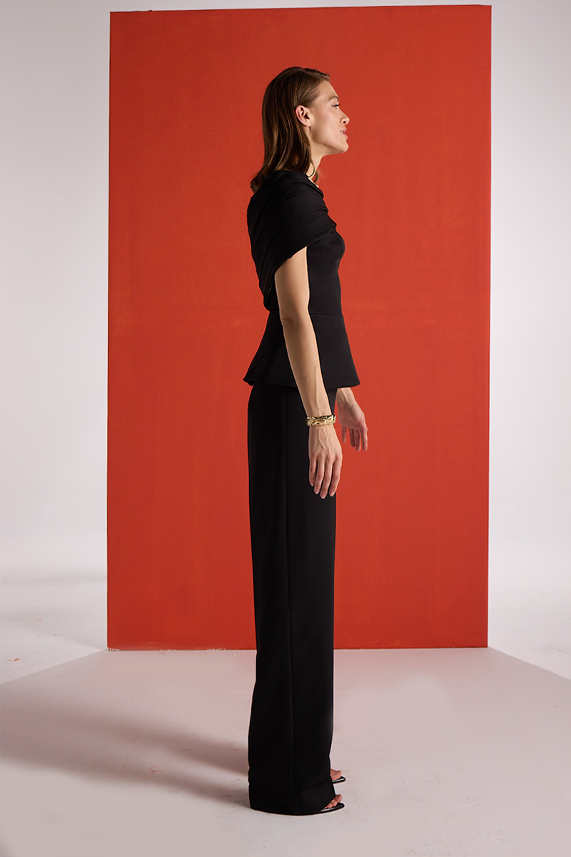 Joanna Andraos black crepe two-piece co-ord set with draped cape, shown from side angle on model.