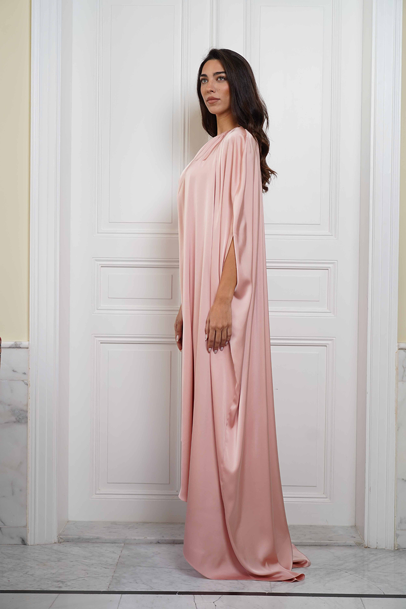 Joanna Andraos Cult Mia X Joanna Andraos soft nude silk gown shown from the side, featuring flowing fabric and elegant design.