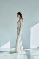 Side view of JINSUN botanically embellished ivory cupro gown showcasing intricate detailing and elegant flowing fabric.