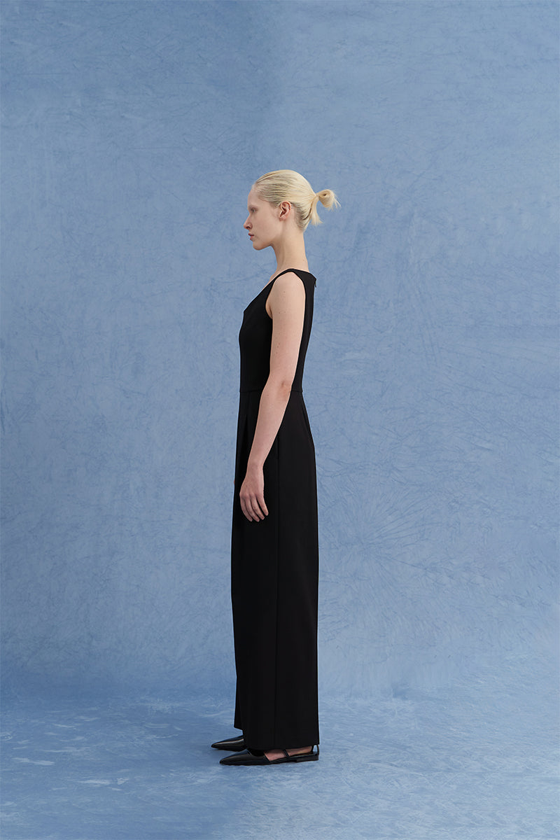 Black asymmetric-beck sleeveless jumpsuit by JINSUN, shown from a side angle, featuring a stylish, modern design.
