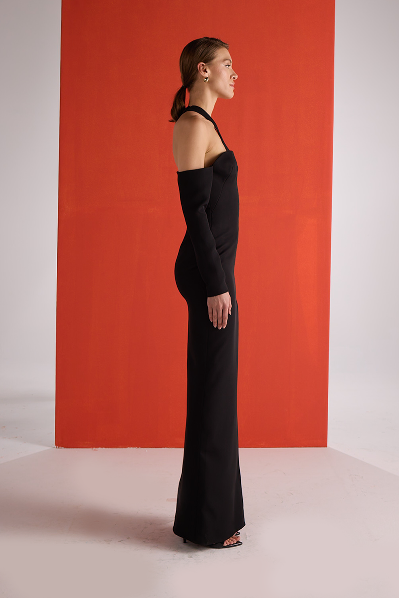 Joanna Andraos black gown with detachable sleeves, side view showcasing elegant design and flowing fabric.
