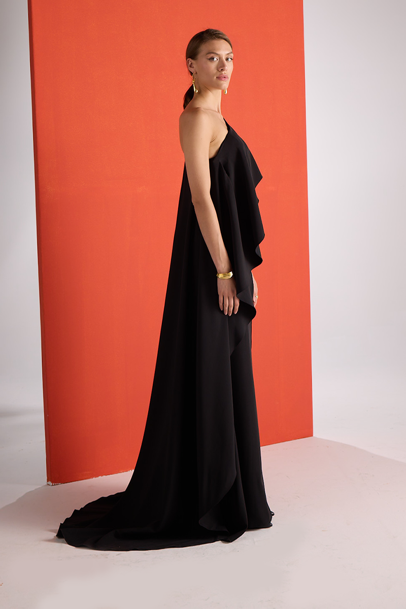 Joanna Andraos midnight elegance one-shoulder gown featuring a sleek silhouette and flowing fabric, shown from a side angle.