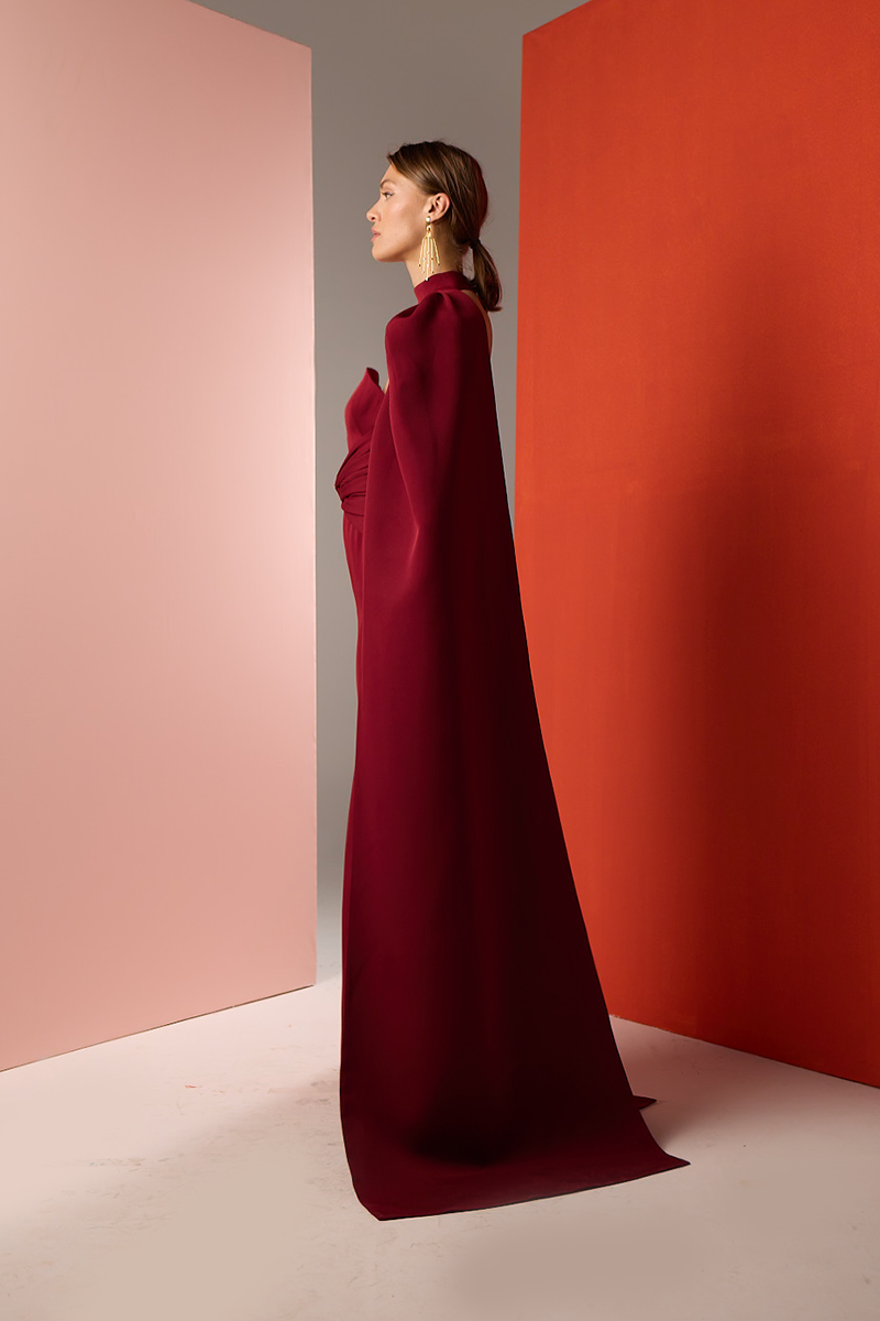 Side view of Joanna Andraos burgundy twist gown, showcasing elegant design and flowing fabric for formal wear.