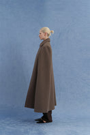 Side view of a long brown wool cape coat by JINSUN, showing its elegant drape and classic collar style.