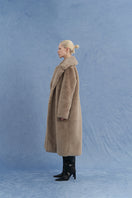 JINSUN oversized shearling coat in brown shown from side view, featuring plush shearling material and relaxed fit.