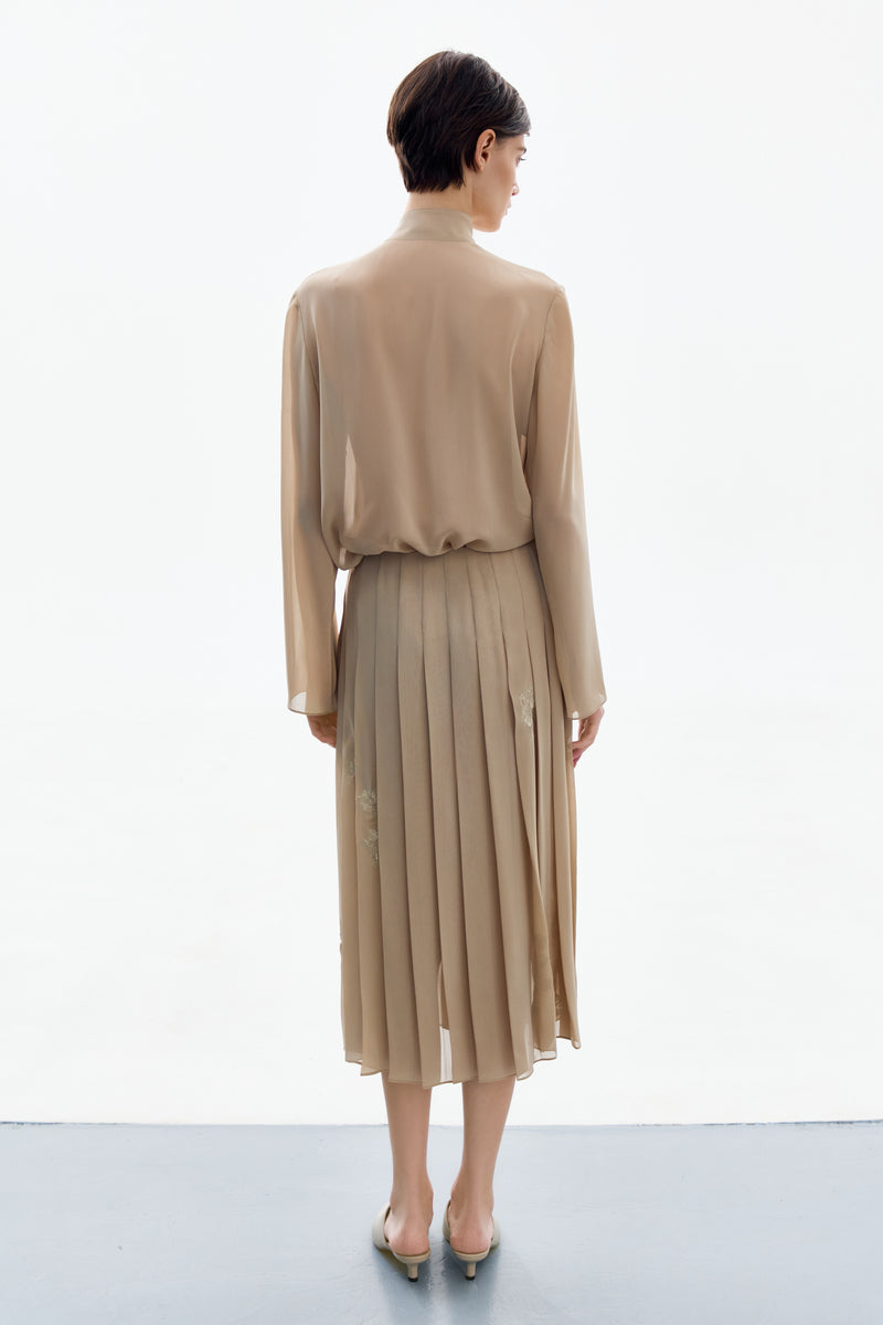 Golden nude pleated midi skirt by DELEGAN, shown from the back with a flowing, elegant design and a fitted waistband.