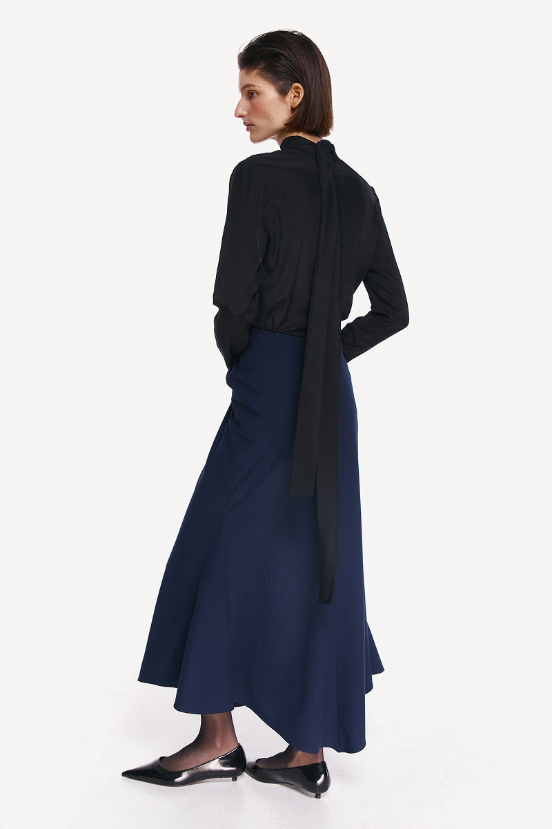 Midnight blue midi skirt by DELEGAN displayed from the back, featuring a sleek, flowing design perfect for stylish outfits.