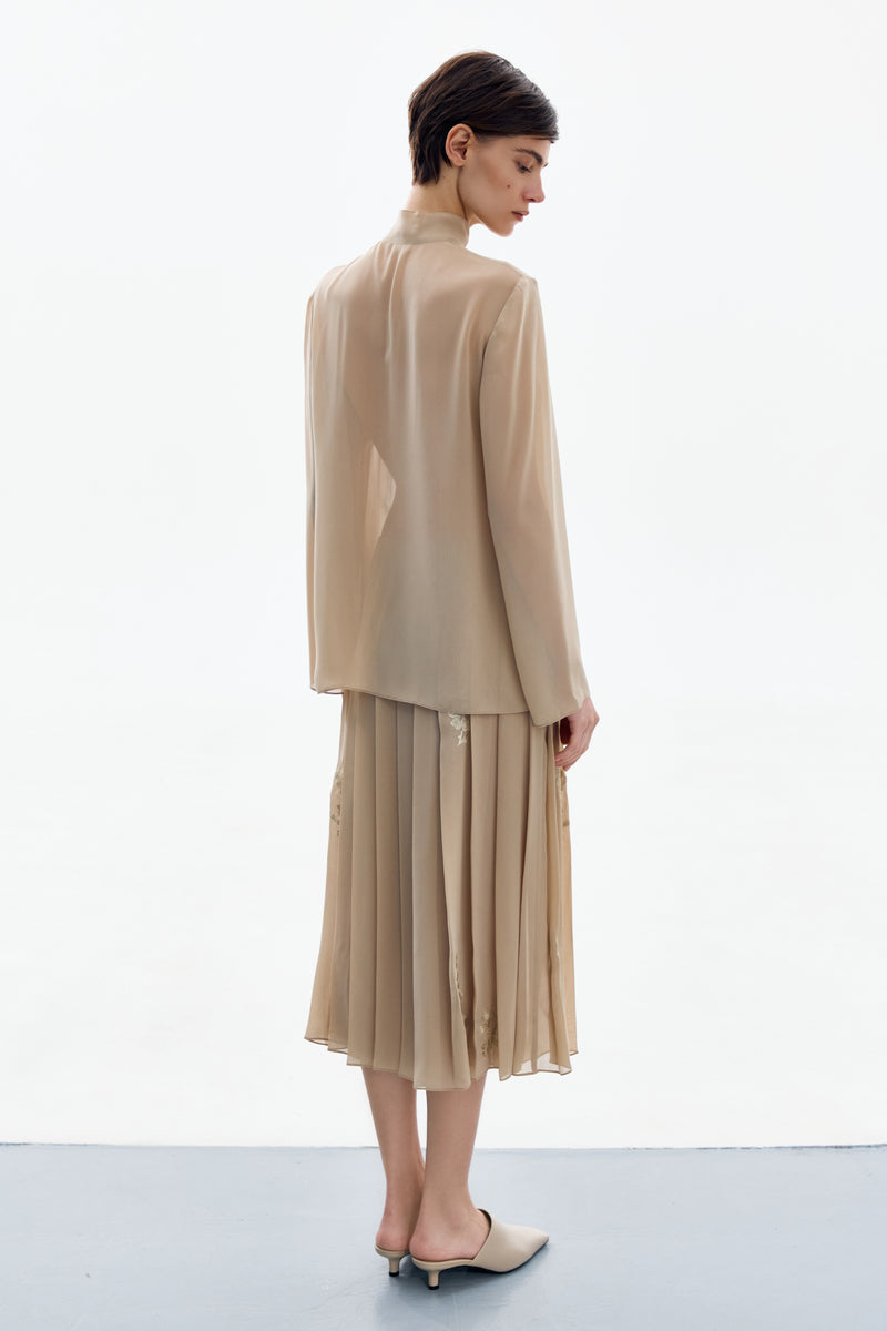 DELEGAN nude gold long sleeve blouse styled back, showing the elegant shirt with a relaxed fit and smooth fabric.