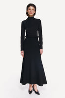 Black KOSSA midi skirt by DELEGAN, styled at the front, showcasing its sleek design and fabric texture.