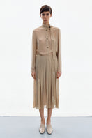 Golden nude pleated midi skirt by DELEGAN, shown from the front with a flowing, elegant design and soft fabric folds.