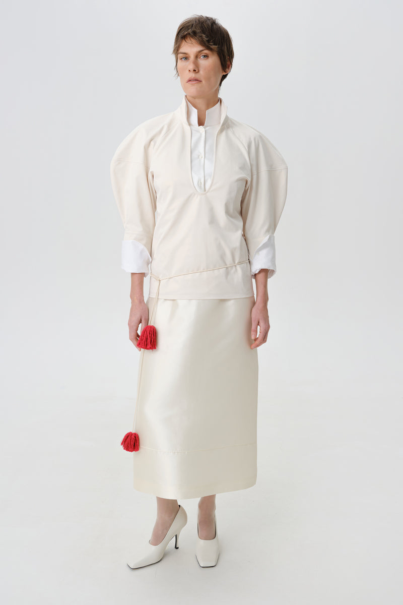 DELEGAN velvet blush silk midi skirt styled at the front, showcasing soft fabric and elegant design.