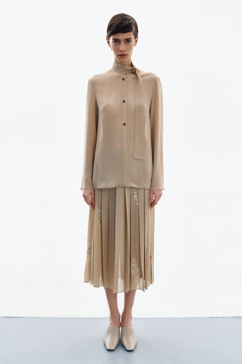 Nude gold long sleeve blouse by DELEGAN, front view showing elegant shirt with fitted long sleeves and smooth fabric.