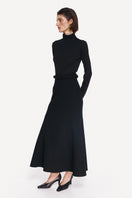 Elegant black midi skirt by DELEGAN, styled side view showcasing the flowy fabric and fitted waist.