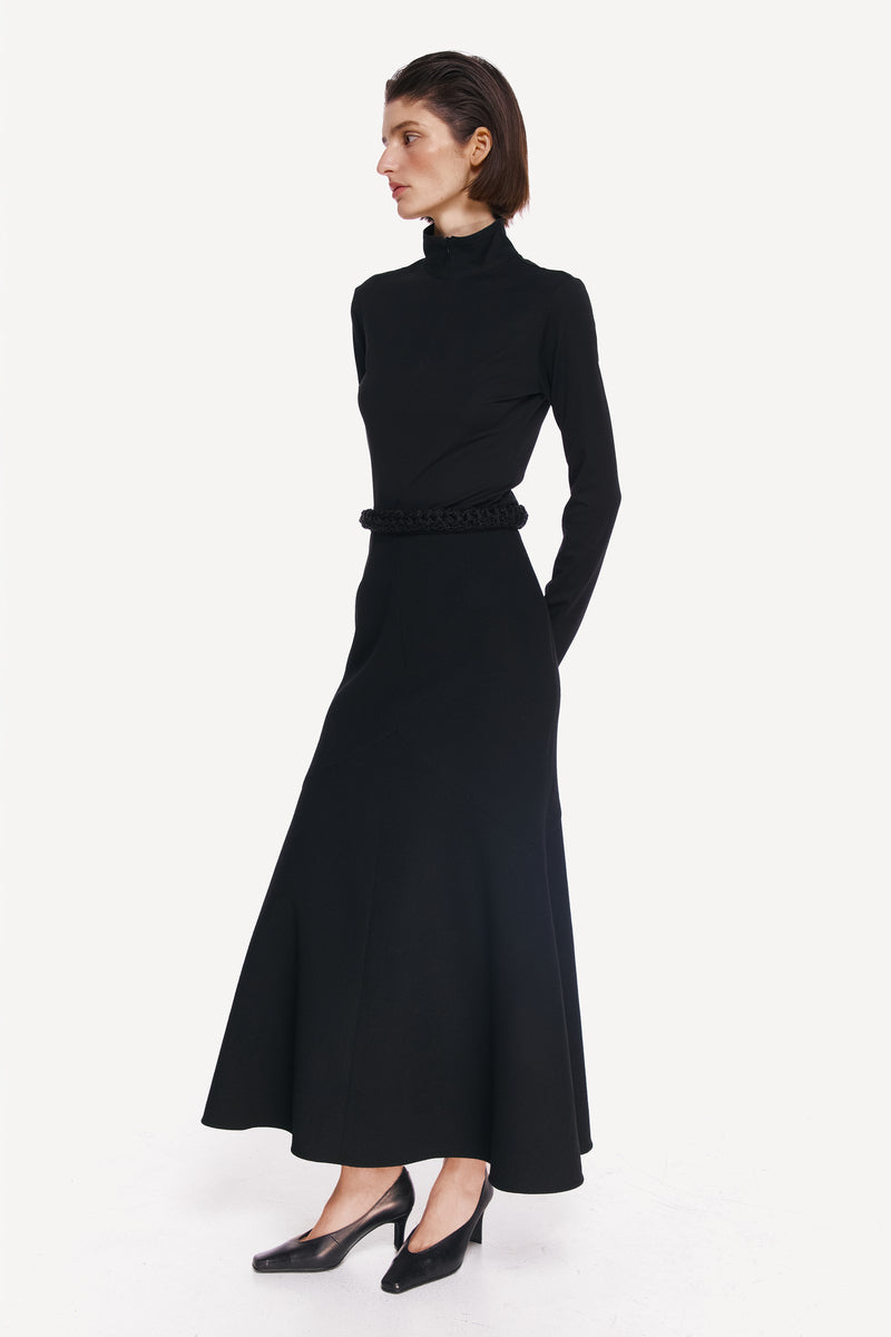 Elegant black midi skirt by DELEGAN, styled side view showcasing the flowy fabric and fitted waist.
