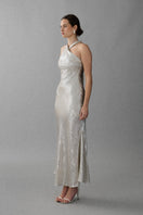 Aisl Celeste Crisscross Ivory Maxi Dress displayed from the side, showcasing its elegant flowing fabric and crisscross bodice design.