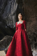Red long sleeve gown with a curved neckline by Tracy Studio, full-length dress featuring elegant design and comfortable fit.