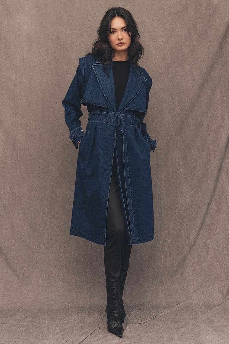 TT Studios TIVOLI ATLANTIC AVE denim trench coat hanging on a rack, showcasing classic design and stylish denim fabric.