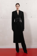 Black Vaska vegan leather coat with belt, tailored fit, featuring long sleeves and classic style, shown in size XS.