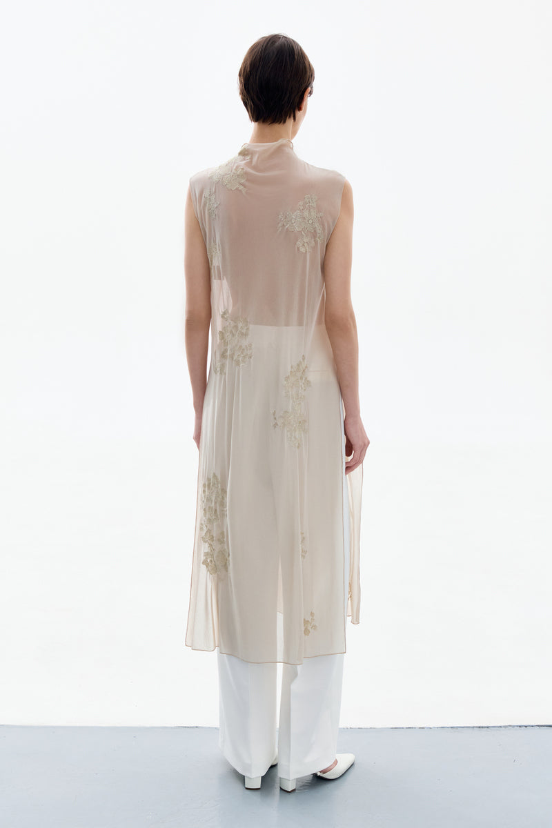 Back view of a woman wearing a brass-colored Delegan Brass Bloom midi dress with a fitted waist and flowing skirt.