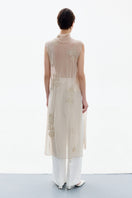 Back view of a woman wearing a brass-colored Delegan Brass Bloom midi dress with a fitted waist and flowing skirt.