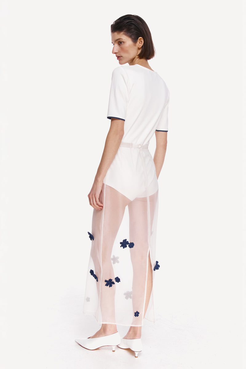 White short sleeve bodysuit from DELEGAN, shown from the back, featuring a fitted design and smooth fabric.