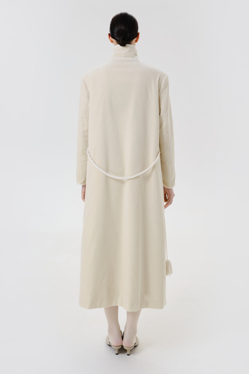 Back view of a stylish ivory velvet coat by Delegan, showcasing its smooth texture and elegant design.