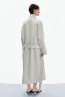 Worn back view of DELEGAN Petal Grey Beige trench coat with classic collar and belt, showcasing stylish outerwear design.