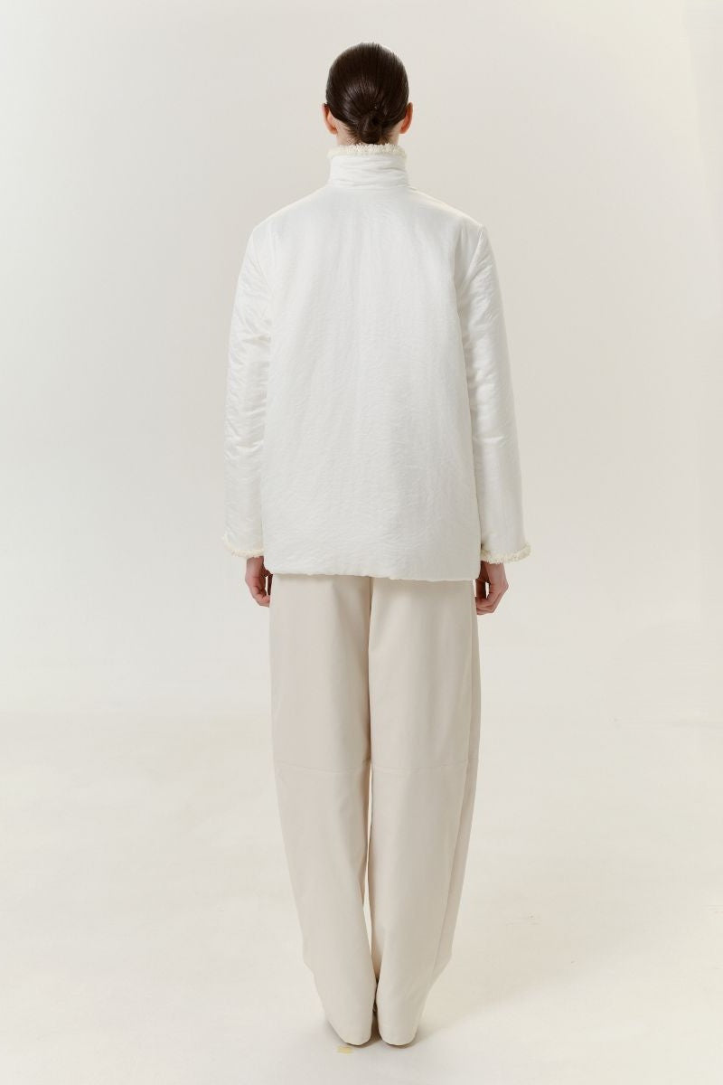 White DELEGAN jacket shown from the back, featuring a sleek design with a collar and long sleeves.