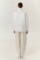 White DELEGAN jacket shown from the back, featuring a sleek design with a collar and long sleeves.