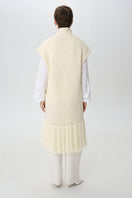 Worn back view of a textured knit DELEGAN cardigan vest featuring a cozy, ribbed design and fitted silhouette.