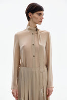 Front view of a nude gold long sleeve blouse by DELEGAN, featuring a sleek design and fitted style.