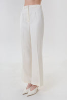 Ivory satin pants with belt by DELEGAN, front view showing smooth fabric and stylish waist detail.