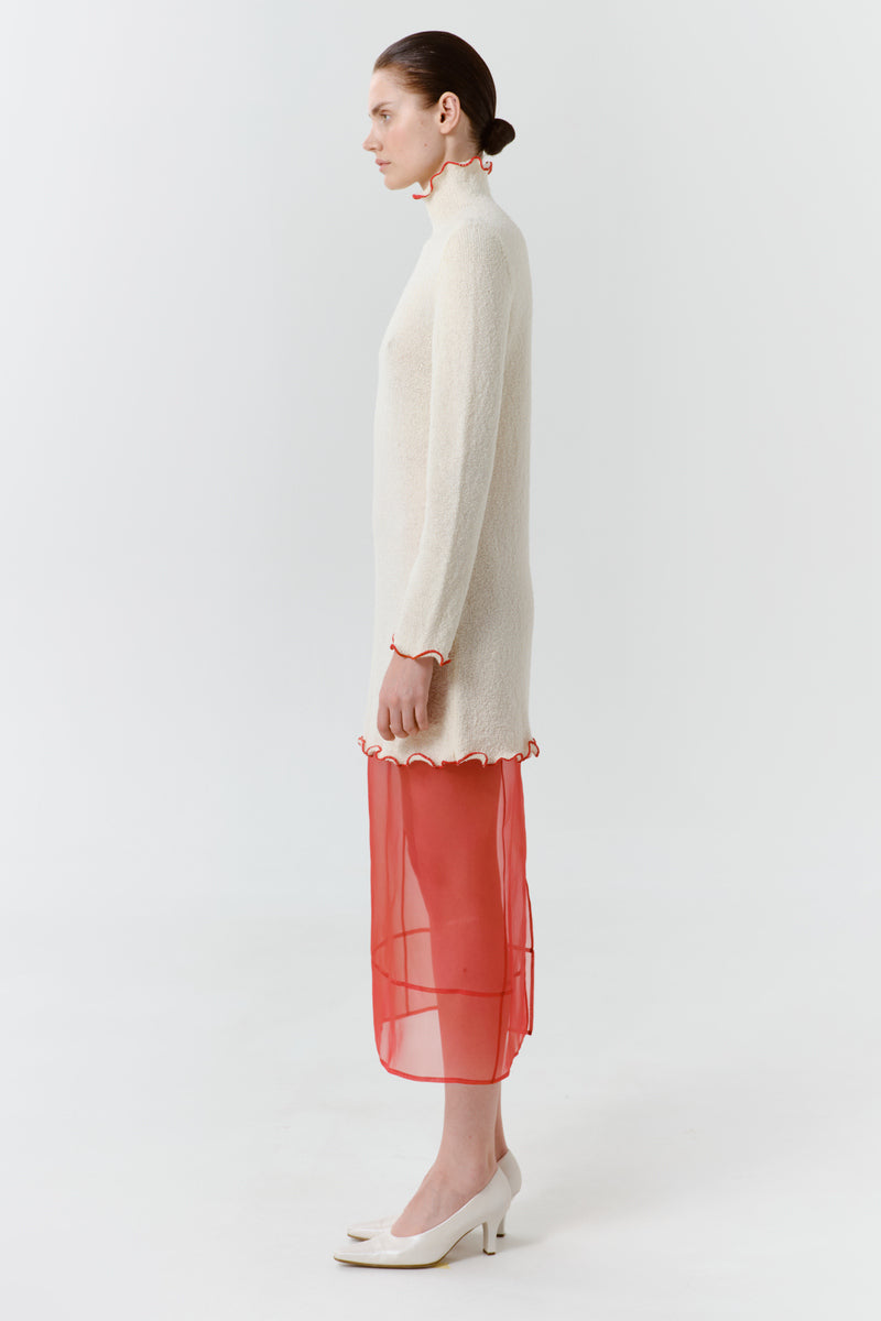 Red blush midi dress by Delegan shown from the side, featuring a fitted bodice and flowing skirt.